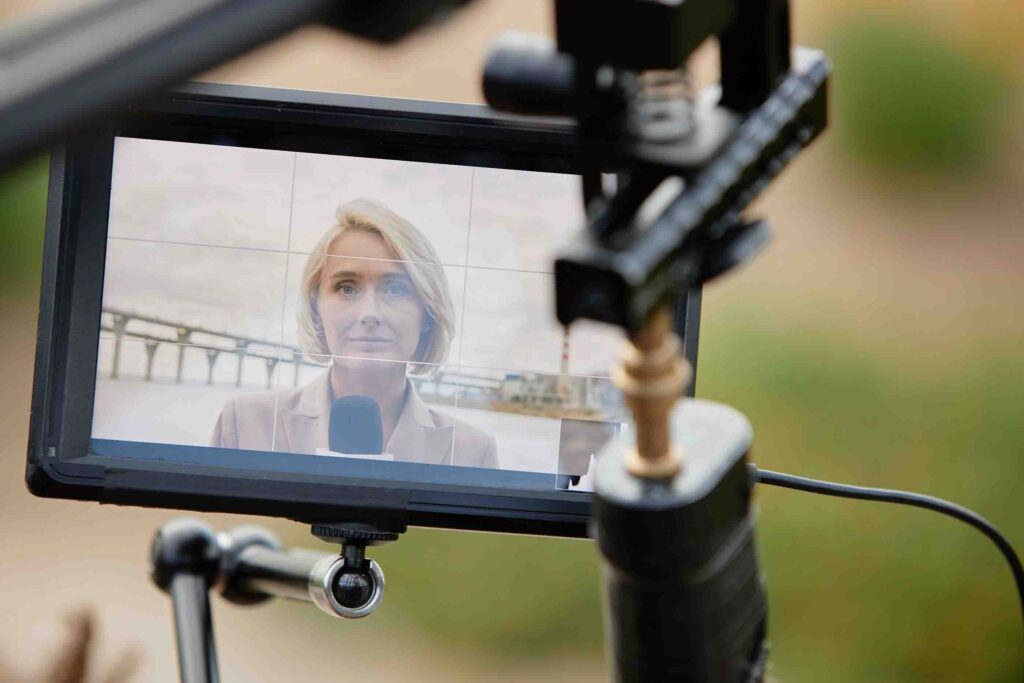 Frau mit Handmikrofon zum Filmen auf einem Monitor