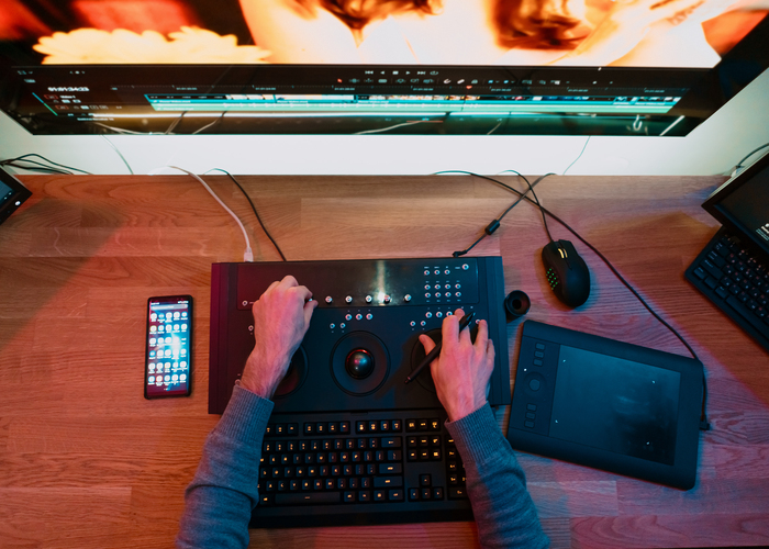 Male Video Editor hands Works with Footage or Video on His control panel of Personal Computer, he Works in Creative Office Studio or home. Neon lights